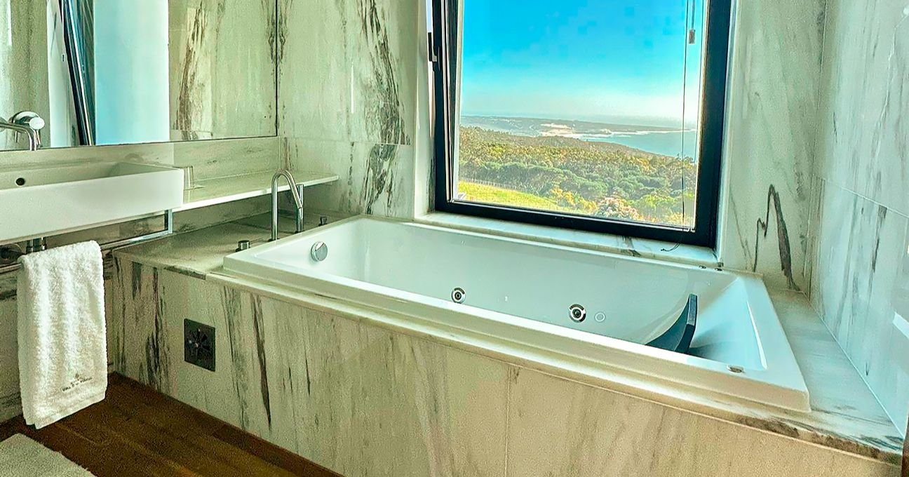 Spacious bathroom with a large jacuzzi bathtub and panoramic window in the Panorama Residence at Quinta Vale da Roca.