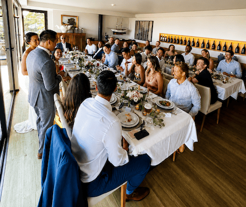 Wedding guests gathered around two elegantly decorated tables for a dinner