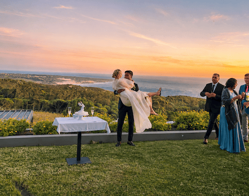 Groom holding a bride after their wedding ceremony with panoramic ocean views near Sintra