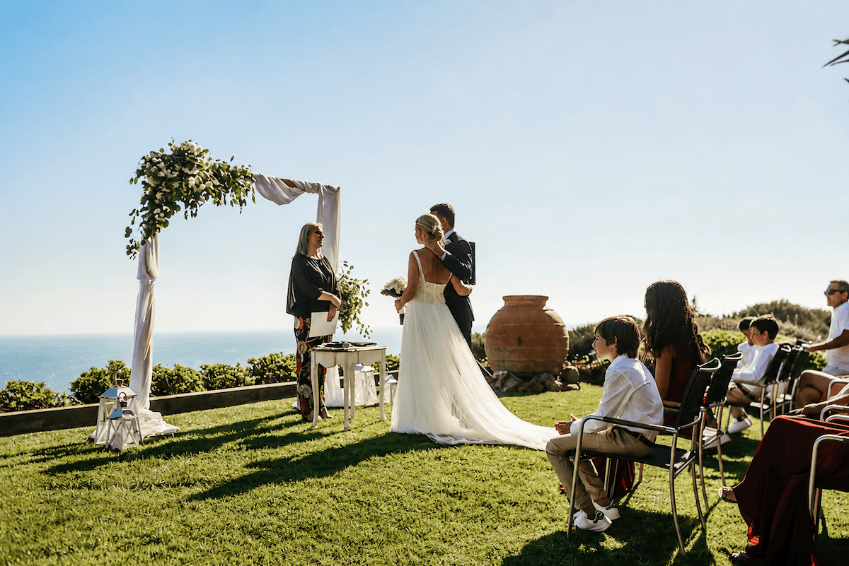 Bride, groom, and guests are at the wedding celebration with panoramic ocean views