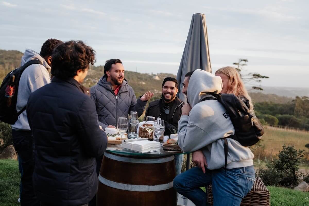 Friends enjoying a wine tasting experience surrounded by vineyards near Lisbon