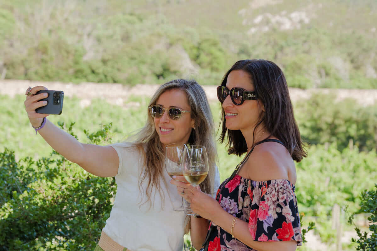 Two women with wine glasses in their hands take a photo