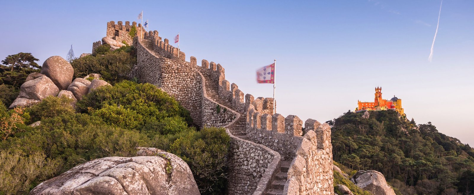 Ancient stone walls and towers of the Moorish Castle overlooking the green hills of Sintra, Portugal.